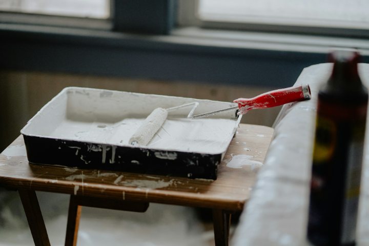 A roller tray on a table covered with a drop sheet, by a window in soft daylight