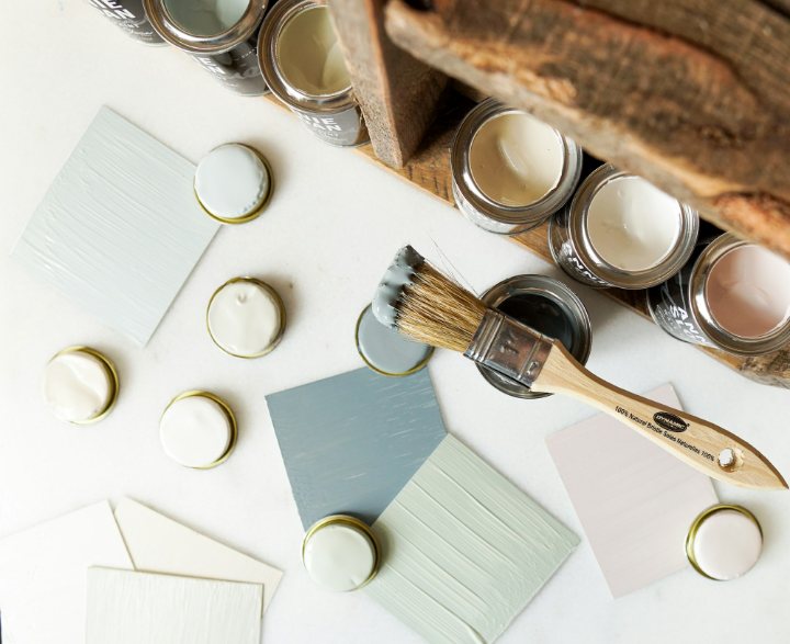 Sample pots, brushed-out color cards and a brush laid out on a pale table